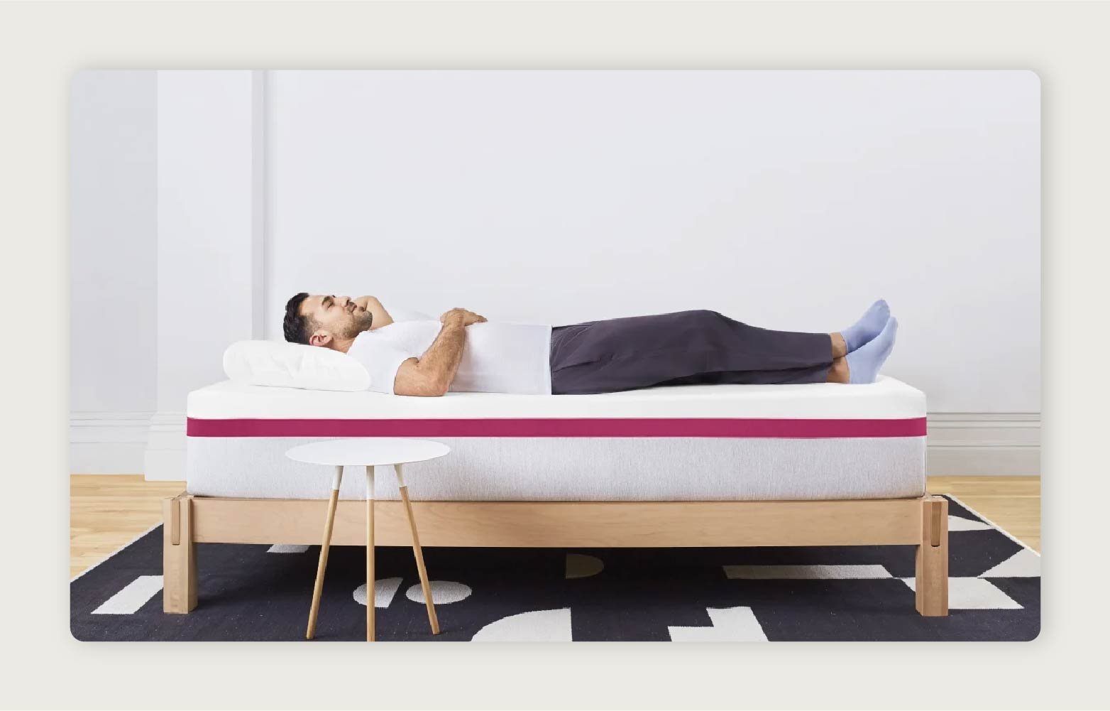 A man in a white shirt lying on a Helix Dusk Mattress placed centrally in a room. 