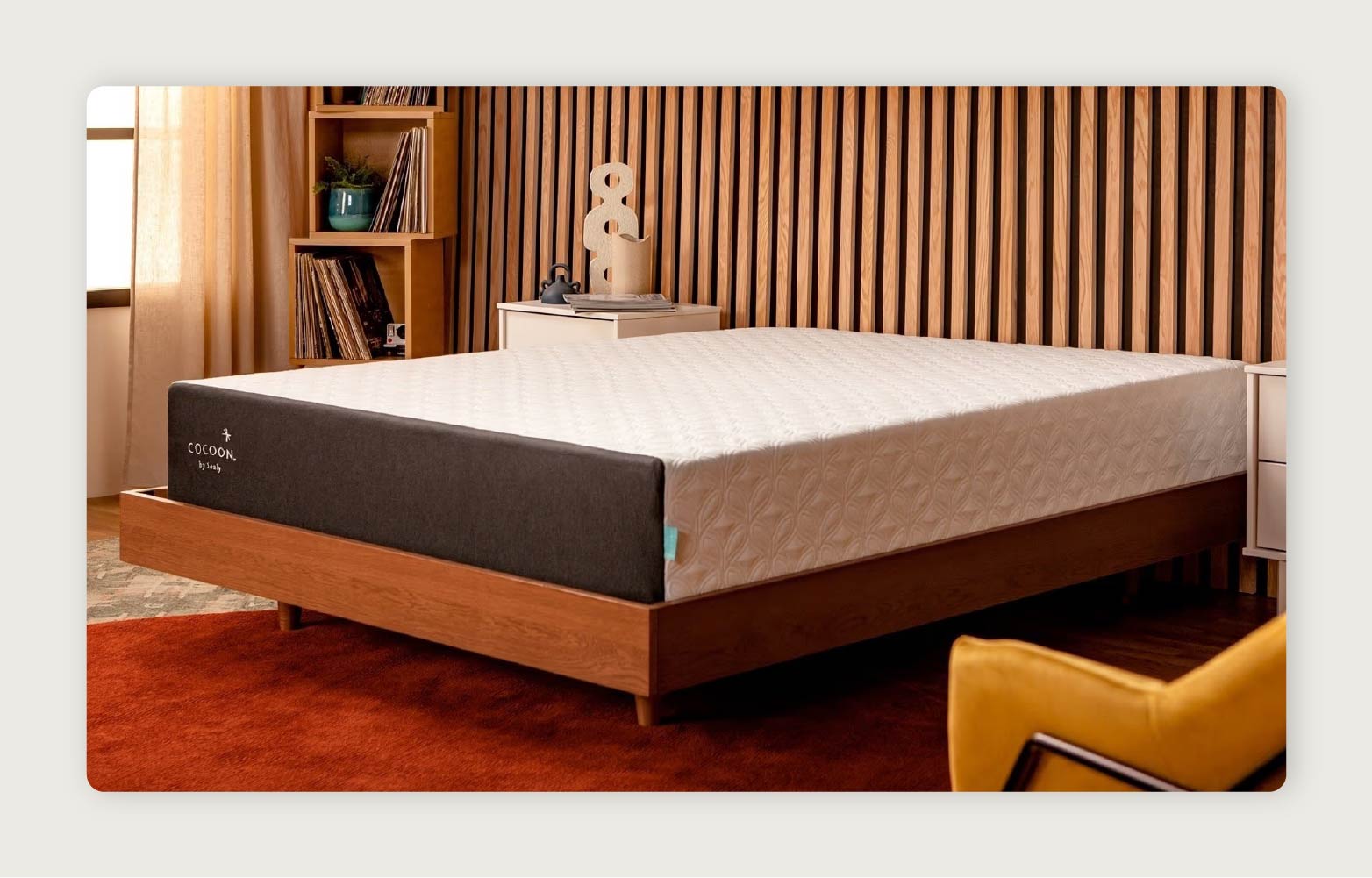 The Cocoon™ Chill Mattress by Sealy in a sleek retro room with wooden shelves featuring records and plants. 