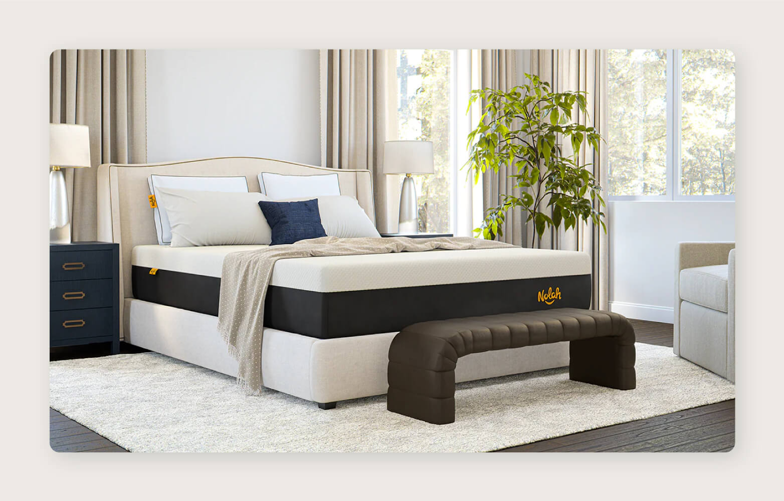 A Nolah Signature Hybrid 12” Mattress with pillows and a throw blanket arranged on top and a dark brown bench at the foot of the bed.