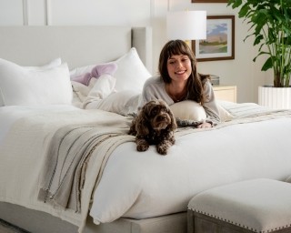 woman and dog laying on a mattress