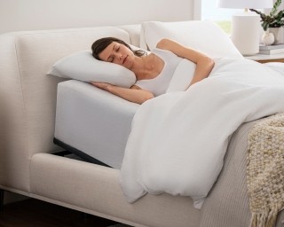 woman laying on mattress supported by an adjustable bed frame