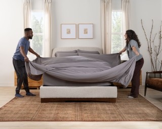 Couple making the bed with SoftStretch sheets