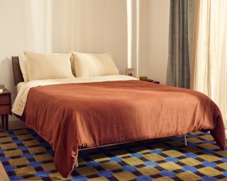 A Purple mattress with a dark orange duvet.