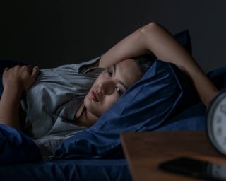 A young woman struggling with insomnia lies awake at night.
