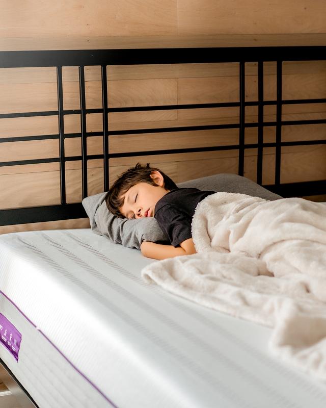 Young boy napping on a Purple Mattress and Pillow