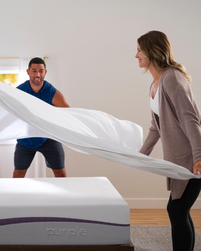 couple putting sheets on a bed