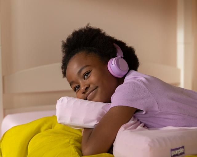 kid hugging kid pillow with headphones on