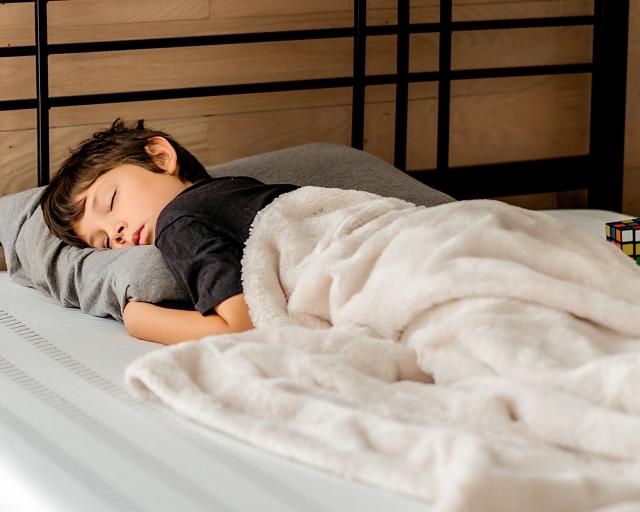 Young boy napping on a Purple Mattress and Pillow