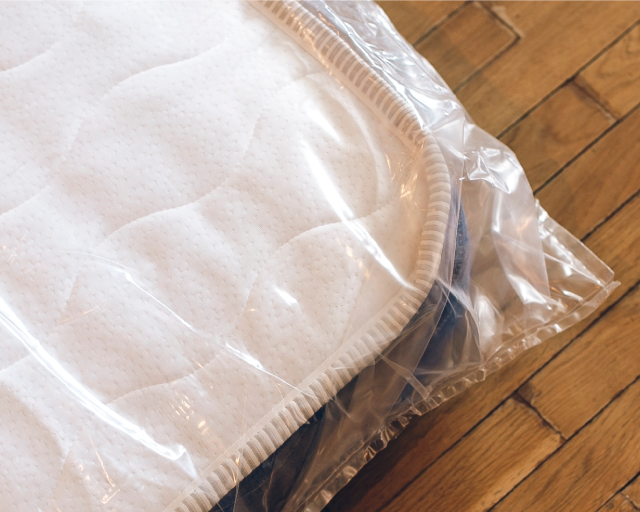 A mattress wrapped in plastic lying flat for storage.