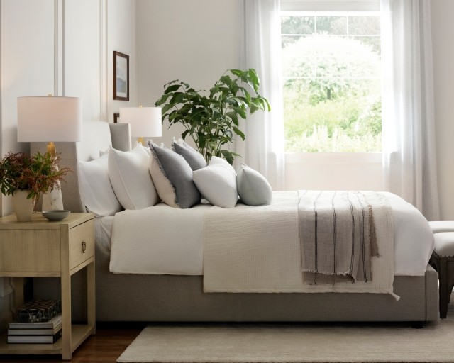 Side view of a fully made Purple Restore™ Hybrid Mattress in a bedroom with nightstands, a dresser, and bench.