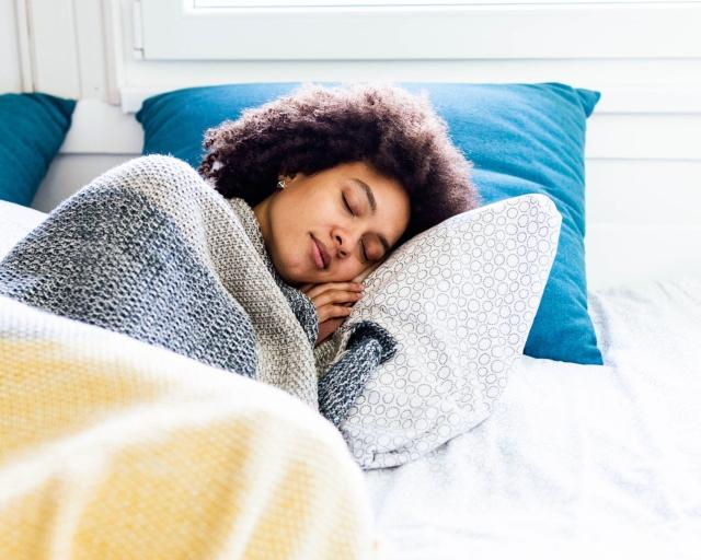 A woman sleeping comfortably on a mattress.