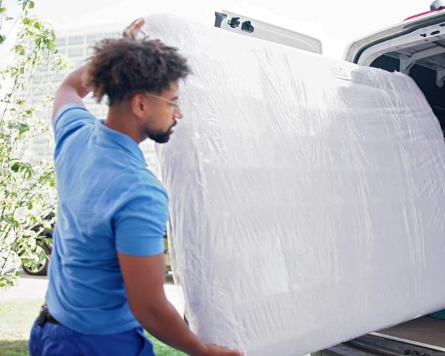 Two people moving a mattress into a moving van