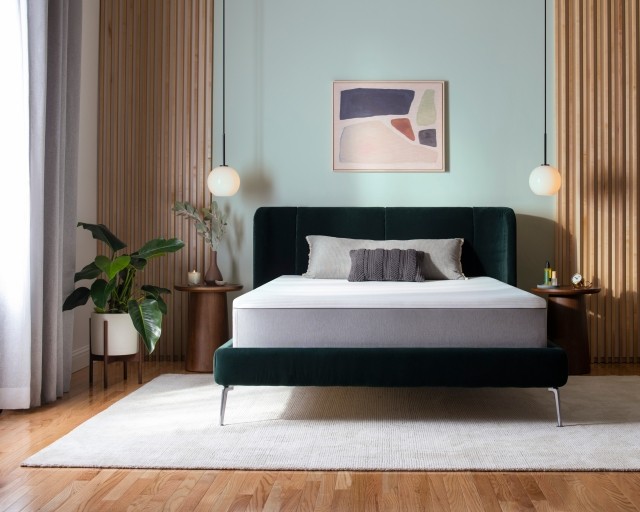 Purple Hybrid mattress unmade on a velvet green bed frame in a bedroom with midcentury modern decor.
