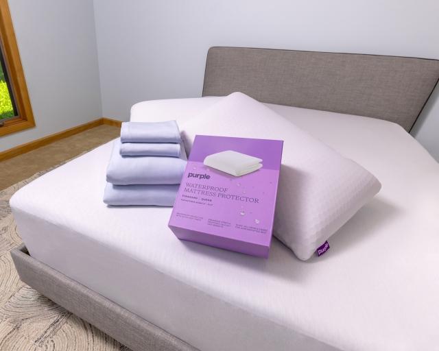 Purple waterproof mattress protector in a box on a mattress.