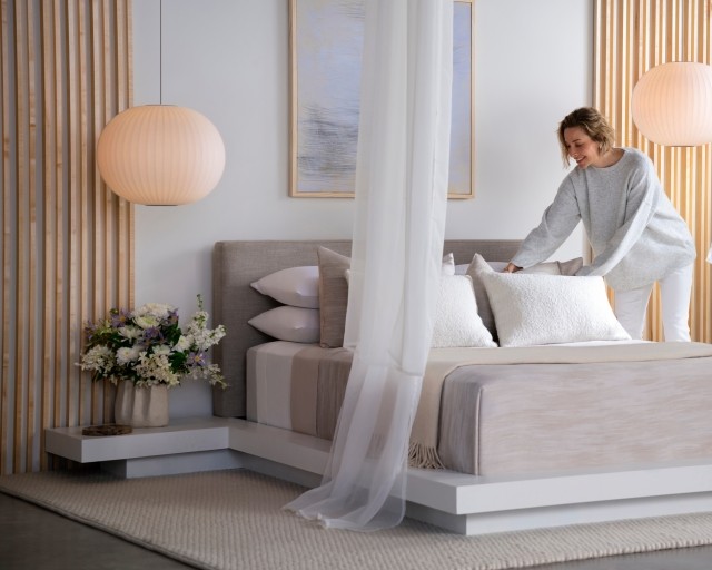 A woman making the bed with a Purple Rejuvenate mattress.