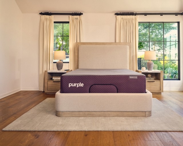 A Purple RestorePremier Hybrid mattress on an upholstered bed frame.