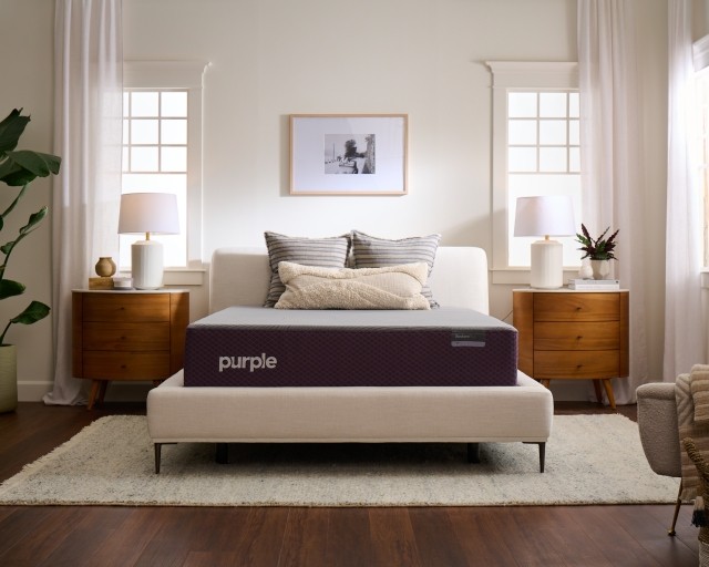A Purple RestorePlus Hybrid mattress in a well-lit bedroom.