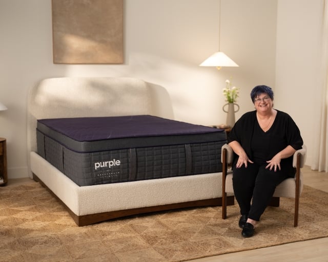 Woman sitting on chair next to RejuvenateUltimate Mattress