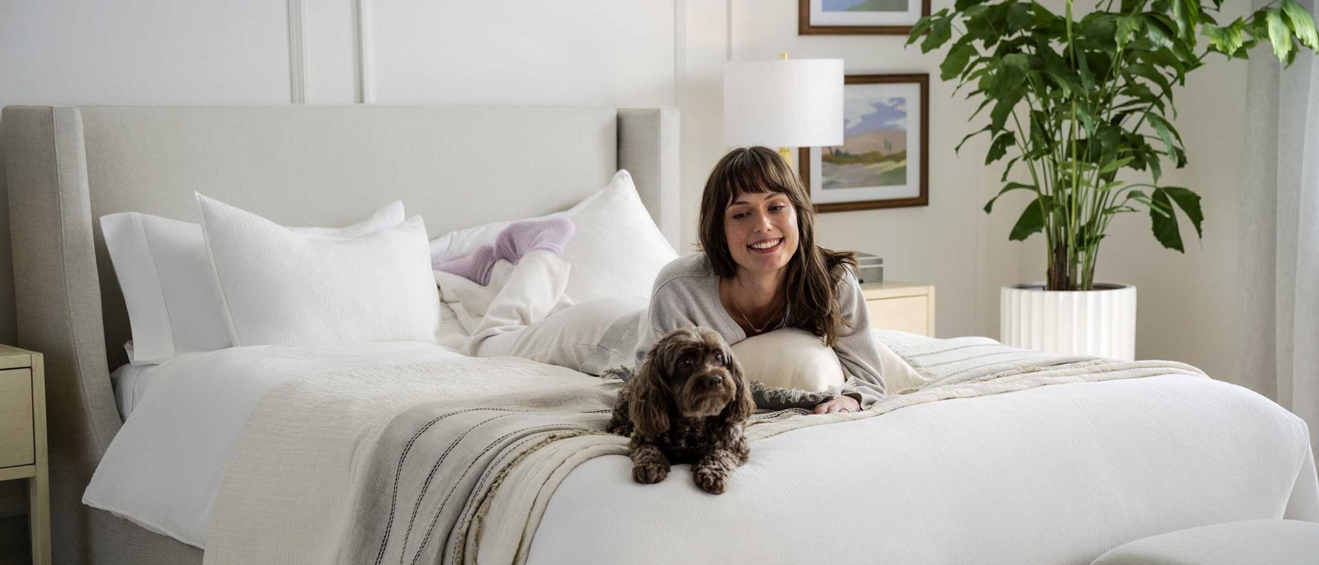woman laying on mattress with dog