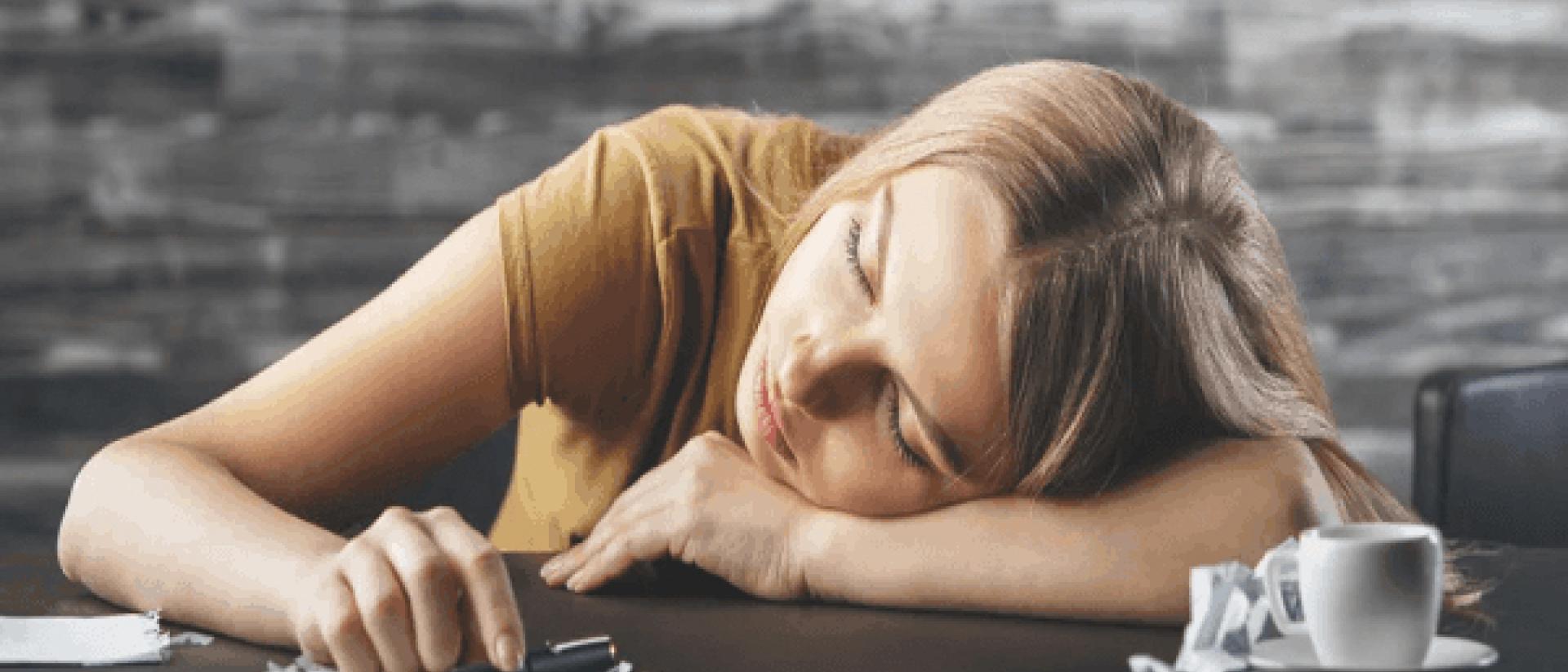 woman taking coffee nap on desk