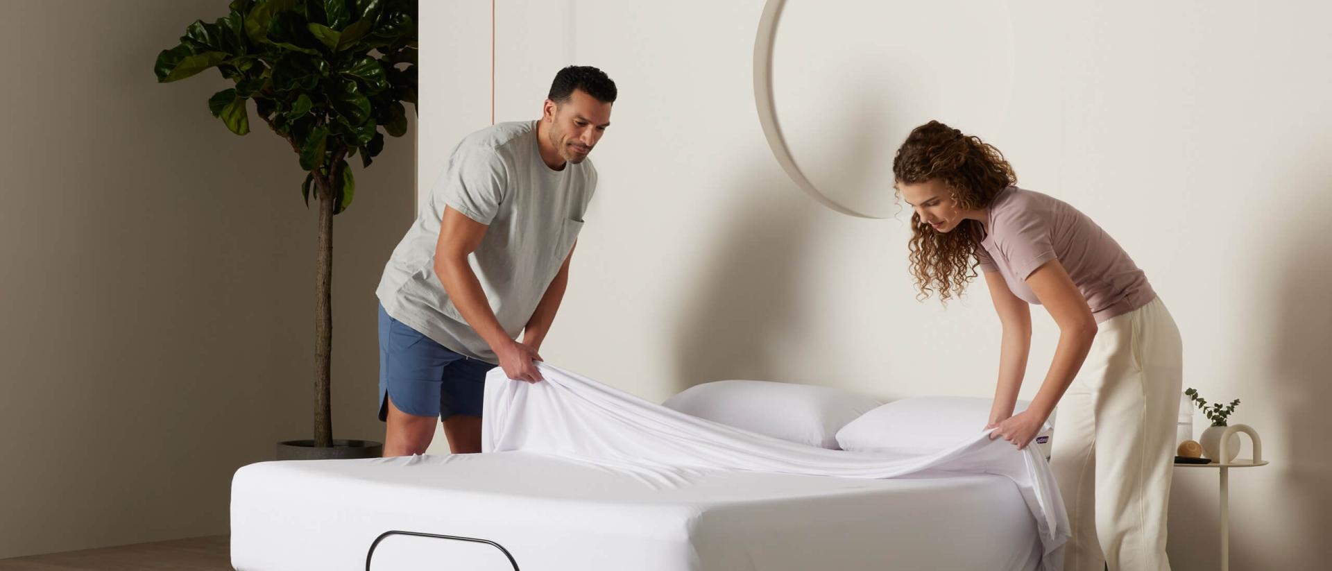 Two people removing a sheet from a Purple mattress.