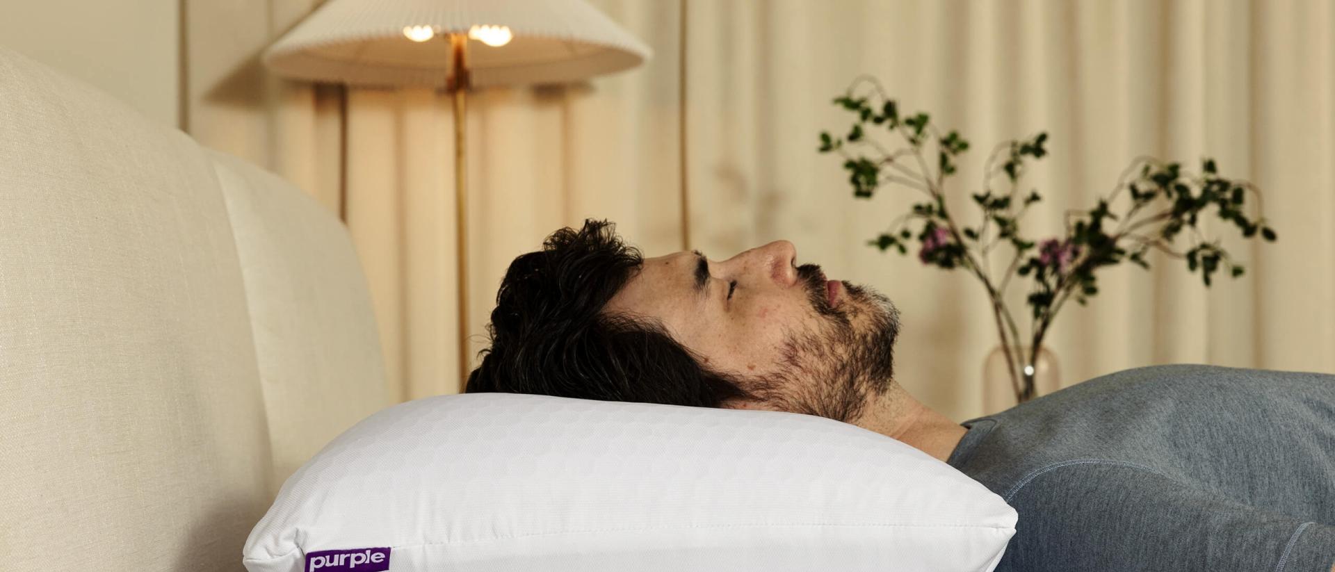 A man sleeps on his back on a Purple pillow