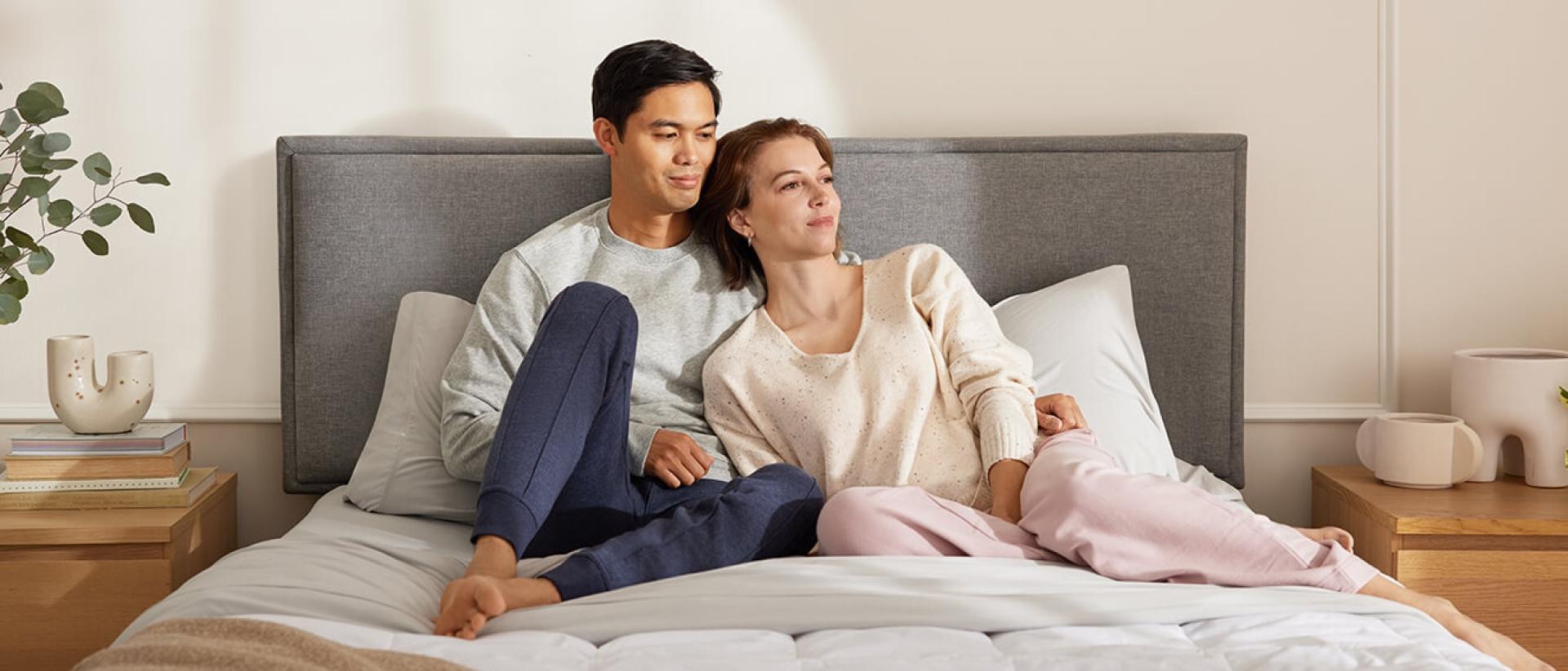 An image showcases a couple lounging on the new blanket they purchased using a blanket size guide.