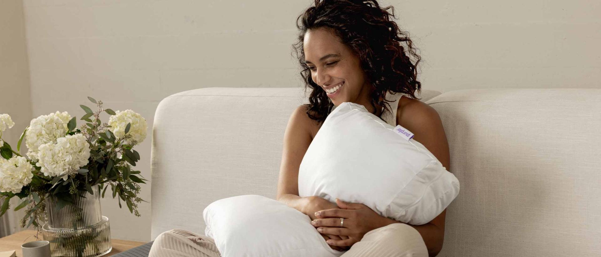 Woman holding a pillow sitting on bed.