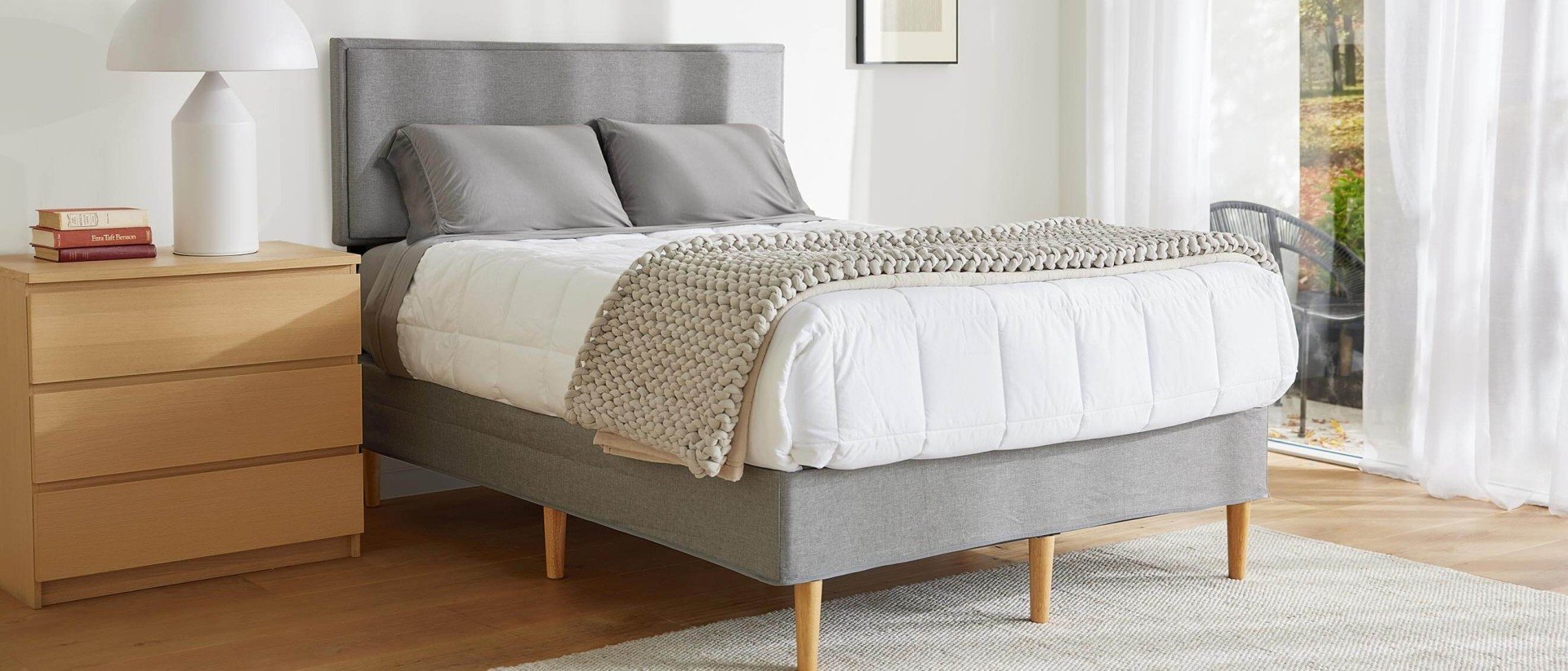 A mattress covered with a duvet and blanket on top of the Purple Bed Frame in a bright bedroom.