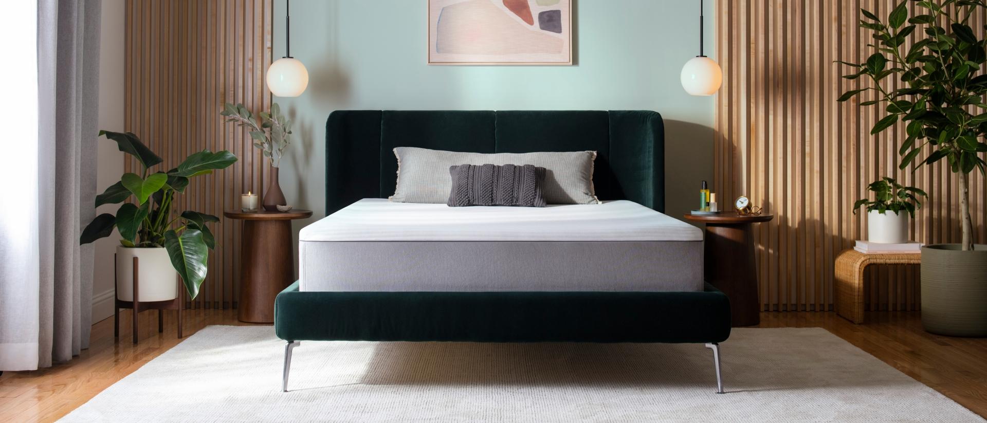 Purple Hybrid mattress unmade on a velvet green bed frame in a bedroom with midcentury modern decor.