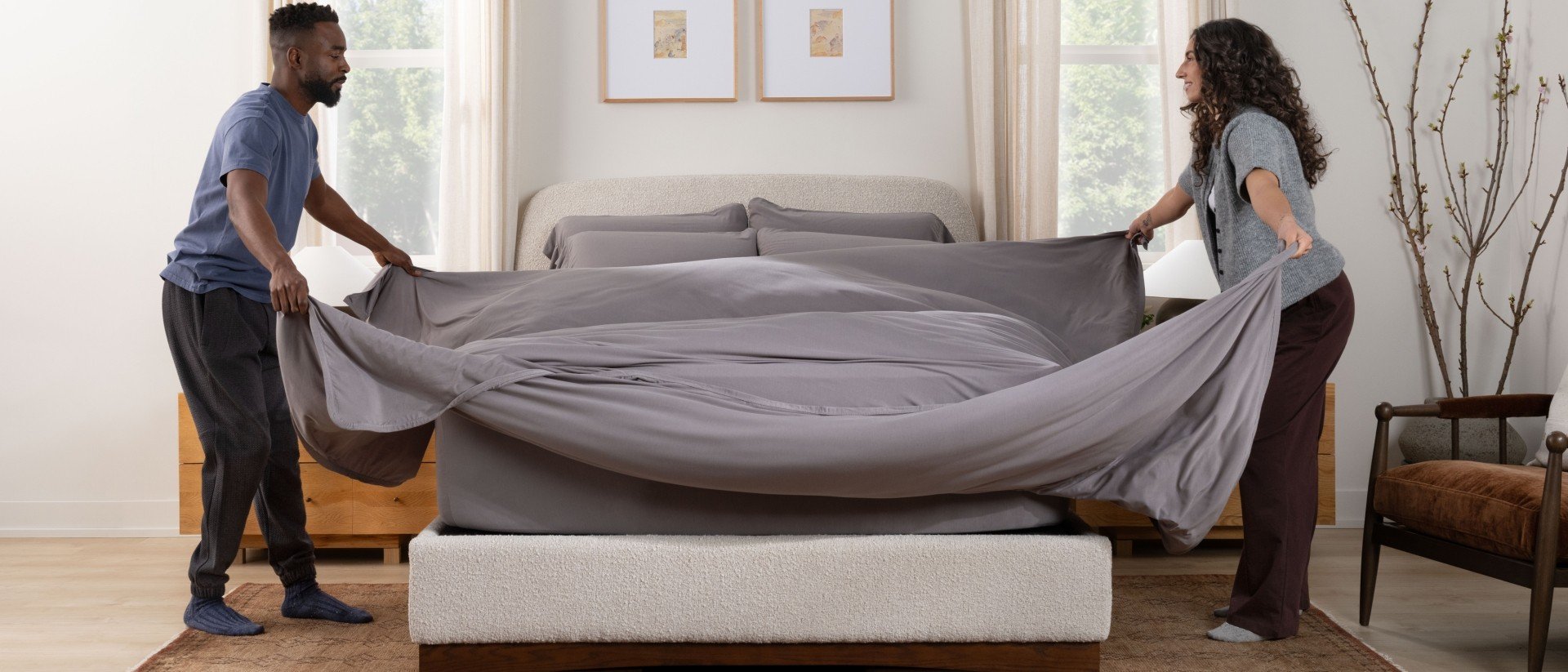 Couple making the bed with SoftStretch sheets