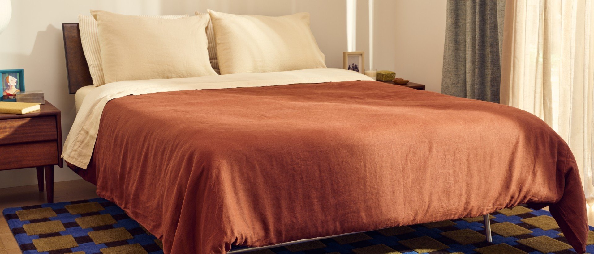 A Purple mattress with a dark orange duvet.