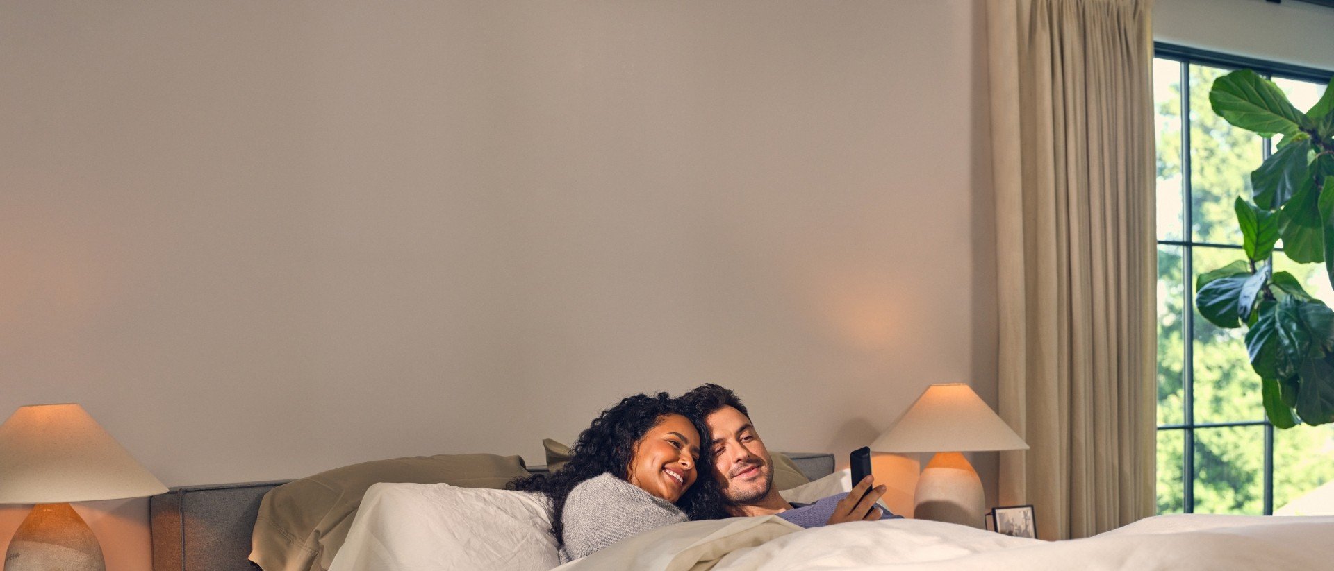 Couple in bed looking at phone 