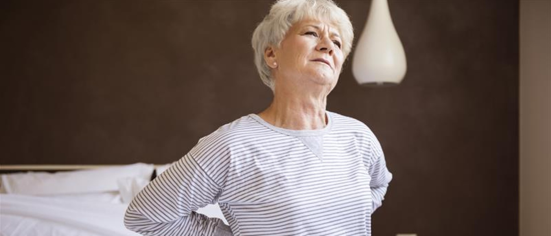 An older woman waking up with back pain.