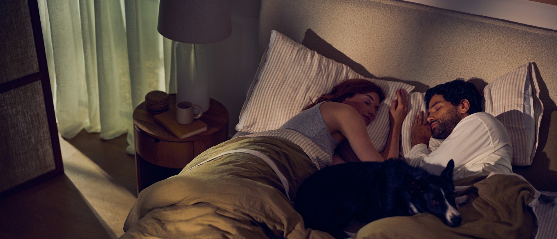 A couple lying on a Purple bed at night.