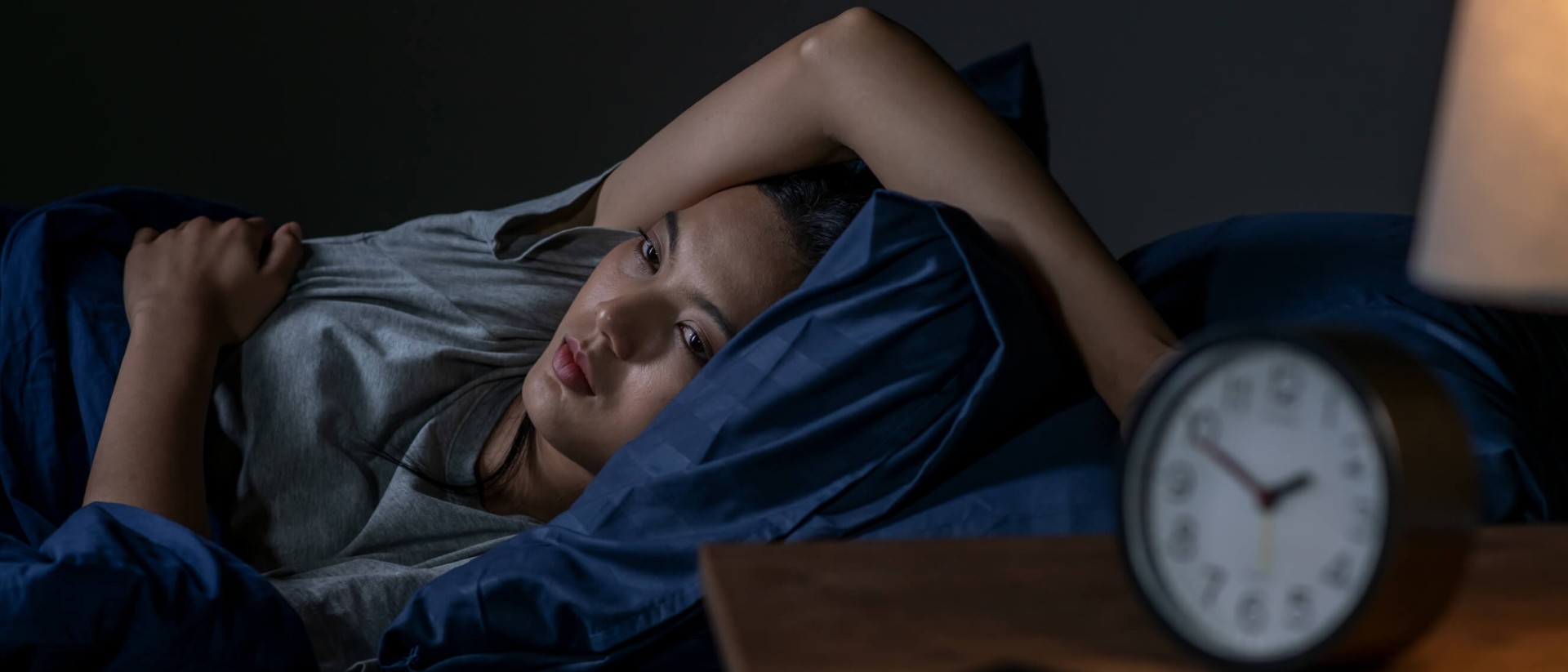 A young woman struggling with insomnia lies awake at night.