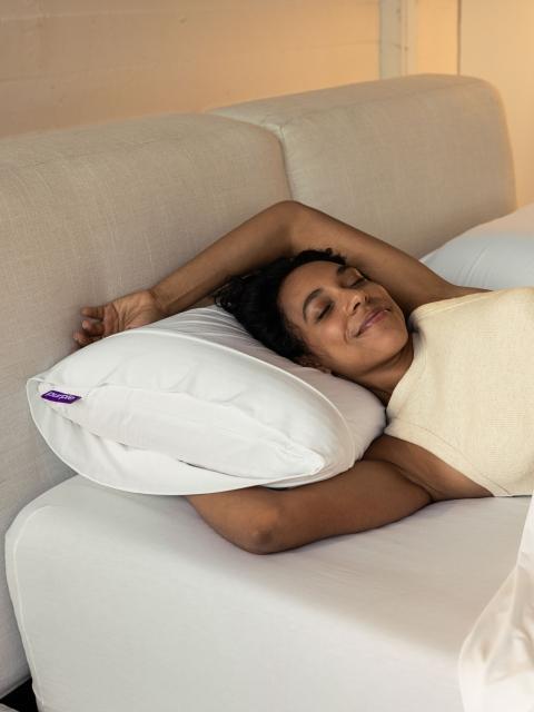 Woman lounging on bed with harmony pillow